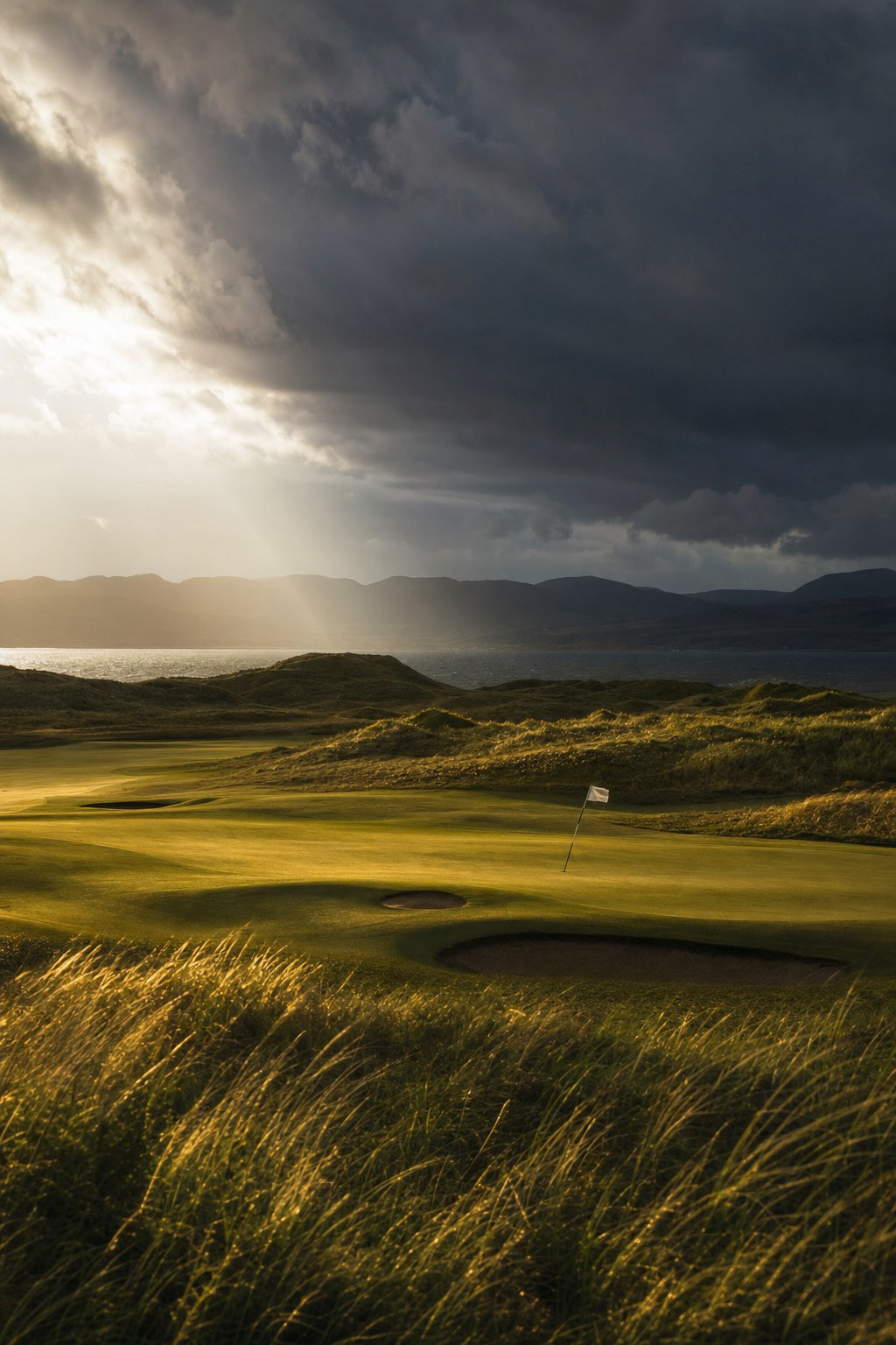 Moody golf wallpaper of storm light breaking over a links fairway
